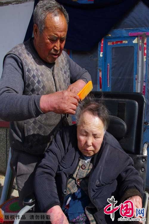  2015年3月9日，每当中午阳光燥热时，吕吉弟都会推着轮椅，在院内和妻子说说话，帮妻子梳理为数不多的头发。