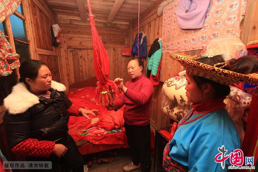  进了女方堂屋，媒人公将随手携来的一把红伞放在神龛上，新娘悄悄把伞取回闺房。家人将早已准备好的12个小绣球依次吊在伞骨上，再把伞收拢放回神龛，以托媒人公向她的心上人捎去一片会心的满足。中国网图片库 曾勇/摄 