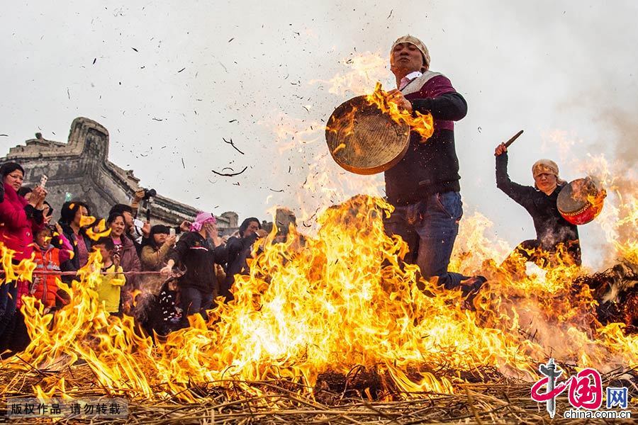  炮竹三响过后，长者点燃熊熊篝火，游行队伍依次从火墩上跃身而过，先是清道旗、标旗、宫灯、锣鼓等，然后是“老爷”坐的八抬大轿，接着村民们跟着一一跃过火墩。中国网图片库 邓飞/摄