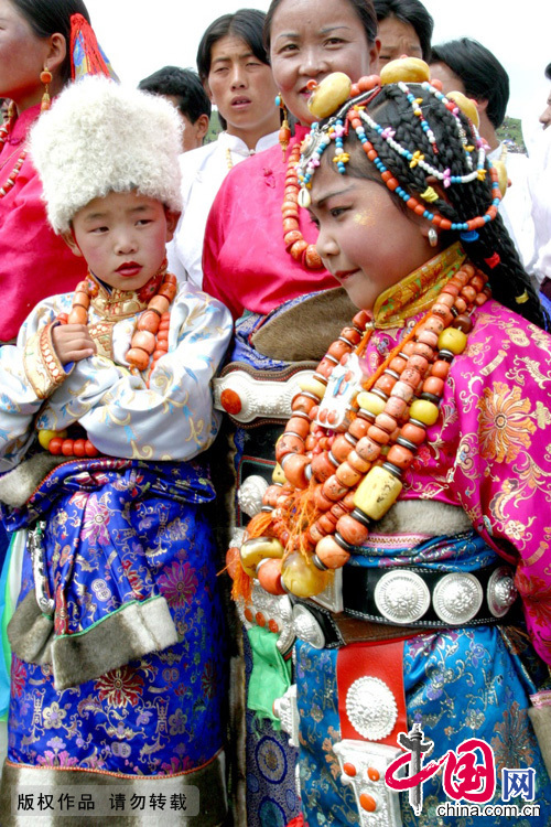 族女性项饰通常都比较大且色彩丰富，垂于胸前显得非常华丽。通常戴多串项链，其材料也多由天珠、玛瑙、珊瑚、蜡贝、松儿石珠等和谐地相互搭配串联而成