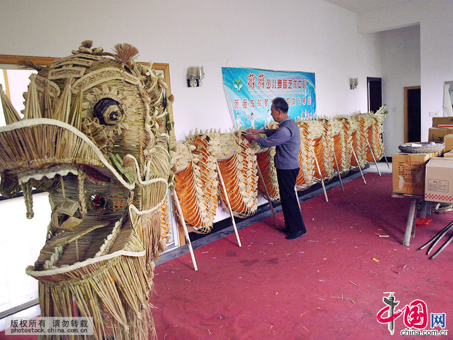 父女俩用黄布缝成“龙胆”穿进龙身，然后整理草龙龙身。中国网图片库 洪永林/摄