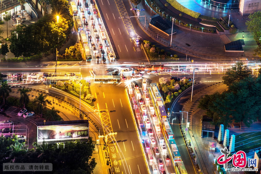 2015年5月12日，摄影师登上深圳的高楼，俯瞰下班晚高峰时段的深南大道，用慢门拍下密集的车辆向前移动的轨迹，在建筑物和灯光的映衬下，光影流转，美不胜收。中国网图片库 邓飞摄