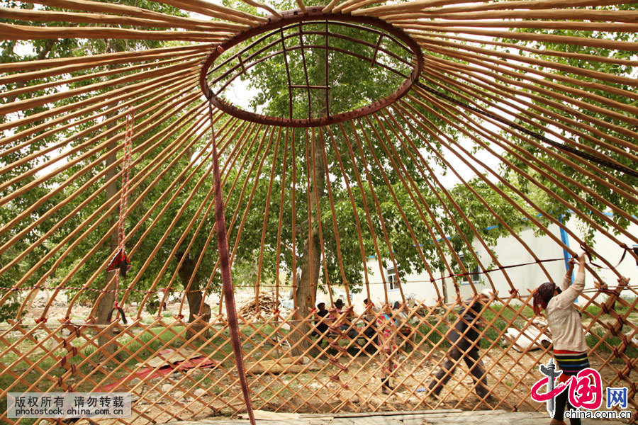  毡房，哈萨克语之为称“宇”，它不仅携带方便，而且坚固耐用，住居舒适，并具有防寒、防雨、防地震等特点夏季来了，塔尔肯邀请了左邻右舍帮自己搭毡房。哈萨克毡房上部为穹形，下部为圆柱形，四壁有网状的木杆搭成整个毡房的骨架，外包白毡。中国网图片库 孙继虎/摄