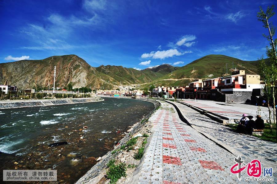 沿河修建的河堤上，几位藏民坐在扎曲河畔聊天。 中国网图片库 王海滨 摄