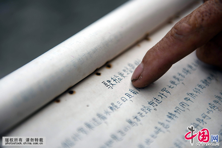  80高龄的老船长苏承芬展示爷爷手抄存留下来的《更路簿》。《更路簿》详细记录了西南中沙群岛的岛礁名称、准确位置和航行针位（航向）、更数（距离）和岛礁特征。中国网图片库 蒙钟德 摄 