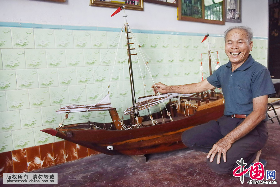  苏承芬展示自己制作的木帆船模型，介绍当年南海捕捞的历史。