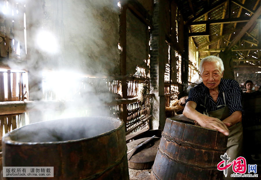 2015年6月18日,四川省岳池县嘉陵乡福兴寺村80多岁的“老油匠”杨辉刚，在用木桶蒸制用于榨取桐油的原料。中国网图片库 邱海鹰/摄