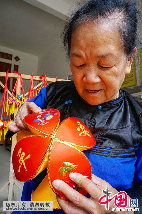 6月21日,在广西靖西县新靖镇旧州街,绣球传承人黄肖琴在对准合拢球瓣.