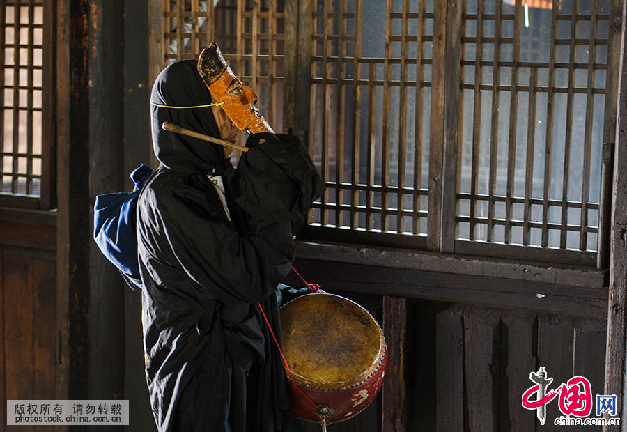  由于演员人少，有的演员身兼数职，这位演员即演菩萨，又得司鼓。傩戏配乐比较简单，一鼓，一锣而已。参加这场演出的演员最大的年逾八旬，最年轻的也过半百。年轻人大多外出打工，宅家的也不愿学习傩戏，因为太累，而且没什么收入。中国网图片库 尹忠 摄 