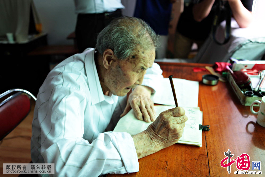  102岁的郭老蘸墨摊纸，写下 “抗战万岁”四个大字。中国网图片库 杨俊琦摄