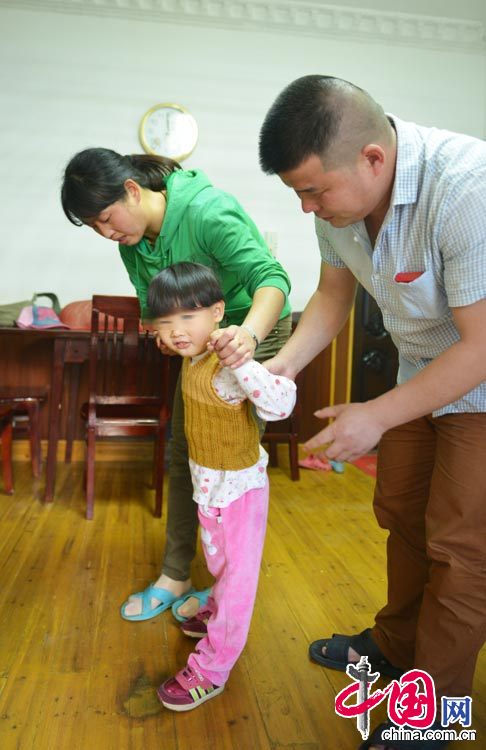 图为今年4月份拍摄，小雅婷在去上海治疗之前，徐建华夫妇扶着她走路，由于逆生长，小雅婷4岁了仍不能走路。中国网图片库