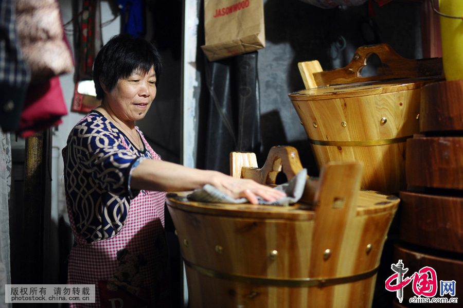戚师傅今年已经63岁了，诸暨人，却说的一口顺溜的杭州话。1985年，22岁的他和老婆楼旗英，带着自家祖传的手艺来杭州。因为当时杭州市民喜欢用木制水桶，所以他的生意不错。图为老婆楼旗英在屋内擦拭老伴刚做好的茶桶。中国网图片库 王川摄