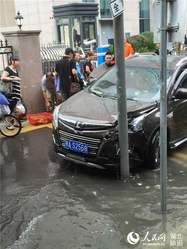 7月15日，武汉暴雨致道路大面积积水，在汉口胜利街，一辆车不慎撞上护栏被撞裂。人民网 李如胜 摄