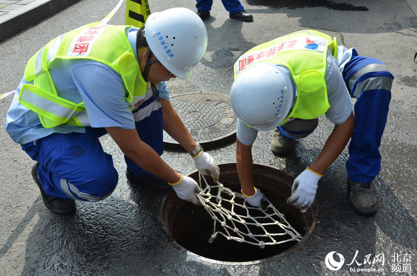 7月23日，北京站东街，北京排水集团的工作人员给清理完的雨水井装上防护网。人民网尹星云 摄