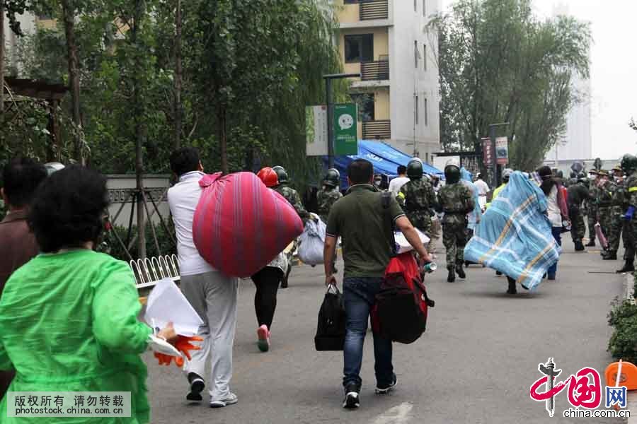 8月18日上午，在位于爆炸核心区周边的清水蓝湾小区居民继续返回家中取物，期间突遇降雨，武警天津市滨海新区支队官兵紧急护送居民撤离小区。中国网图片库 王胜涛摄