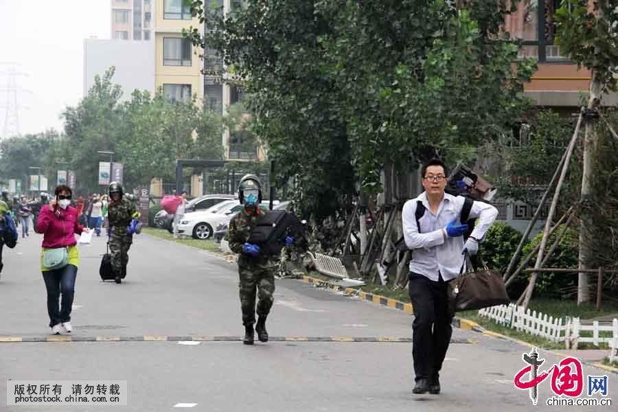 8月18日上午，在位于爆炸核心区周边的清水蓝湾小区居民继续返回家中取物，期间突遇降雨，武警天津市滨海新区支队官兵紧急护送居民撤离小区。中国网图片库 王胜涛摄