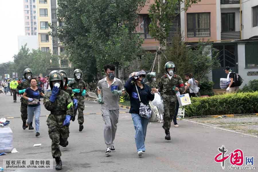 8月18日上午，在位于爆炸核心区周边的清水蓝湾小区居民继续返回家中取物，期间突遇降雨，武警天津市滨海新区支队官兵紧急护送居民撤离小区。中国网图片库 王胜涛摄