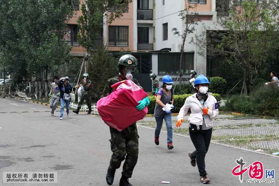 8月18日上午，在位于爆炸核心区周边的清水蓝湾小区居民继续返回家中取物，期间突遇降雨，武警天津市滨海新区支队官兵紧急护送居民撤离小区。中国网图片库 王胜涛摄