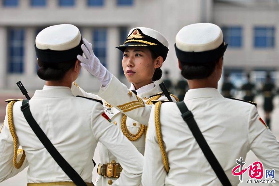 2015年8月28日，一位女兵在为同伴纠正动作，“严抓细训”是她们方队的一贯态度。 梁振摄