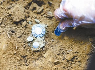 现场发掘出的帽徽 供图/龙越慈善基金会