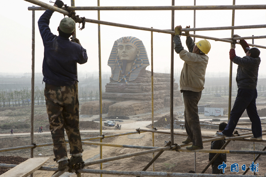 2015年3月27日，安徽滁州一创意园区，工人们在一尊山寨“狮身人面像”附近施工。该园区还仿建了金字塔、天坛等中外著名的建筑，用于影视拍摄背景和招揽游客。 中国日报记者 匡林华 摄影