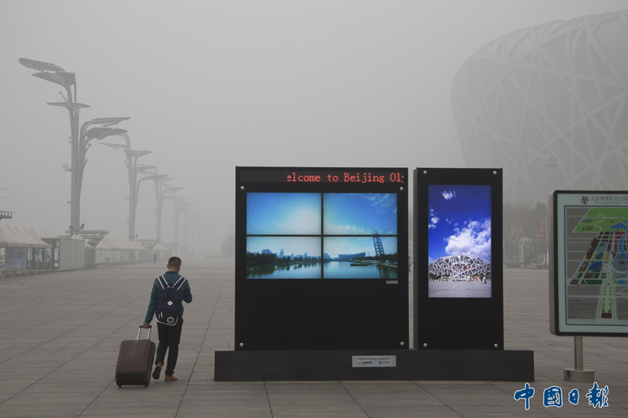 2015年12月1日，北京，游客在雾霾中游览奥林匹克公园。11月30日，北京市空气重污染应急指挥部首次启动橙色级别的预警，连续5天的重雾霾引发民众对红色应急预警机制启动迟缓的讨论。 中国日报记者 匡林华 摄影