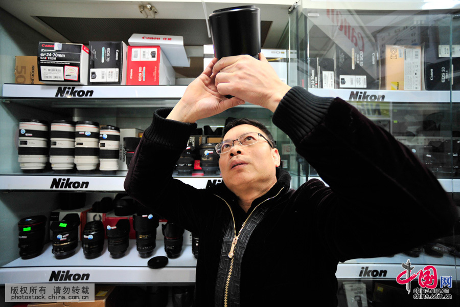 詹春明师傅在他的“相机医院”内查验维修完毕，等待顾客领取的相机镜头。中国网图片库 王伟摄