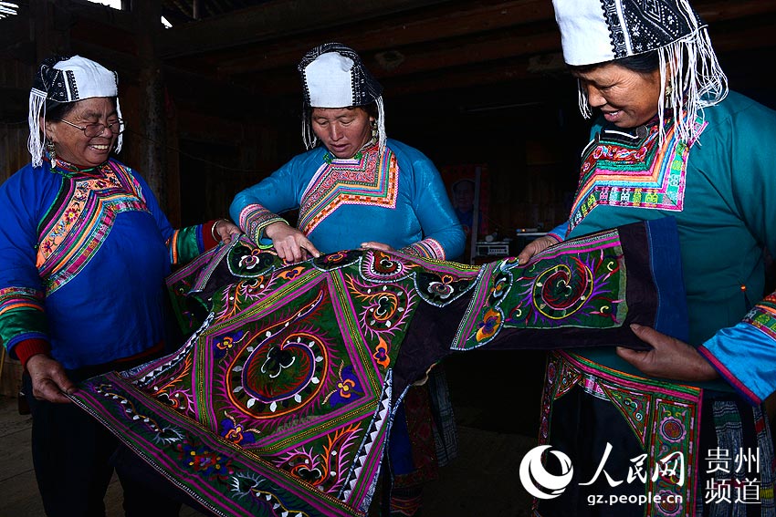 1月29日，平江乡滚仲村苗族妇女在查看即将制作完成的“百鸟衣”。王炳真 摄