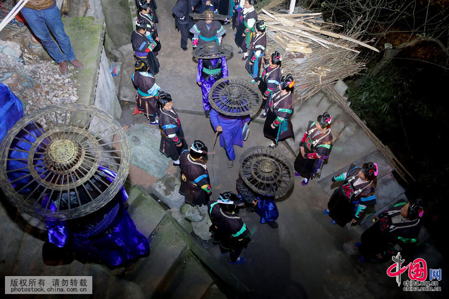  出鼓，鼓头身穿缎长衫，头戴已抽掉粽粑叶只剩竹篾骨架的斗笠，即把木鼓由家中抬到寨脚河沙坝的踩鼓场架起，咚咚达达地敲响起来。中国网图片库 张晖 摄