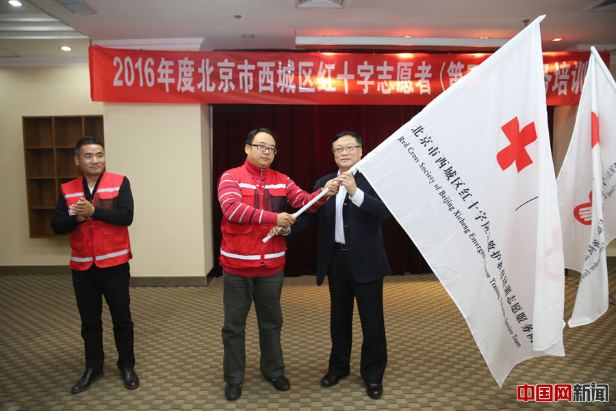 北京市西城区红十字会党组书记、常务副会长王志东为新成立的志愿者队伍授旗。西城区红十字会许伯宁摄
