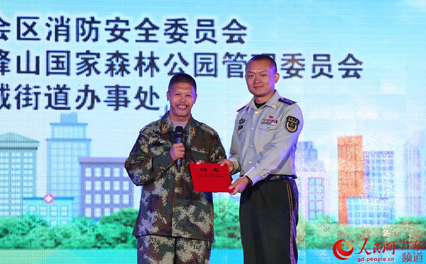 新會消防大隊政治教導員郝博（右）為陳曉均（左）頒發“榮譽消防員”聘書。（新消 供圖）
