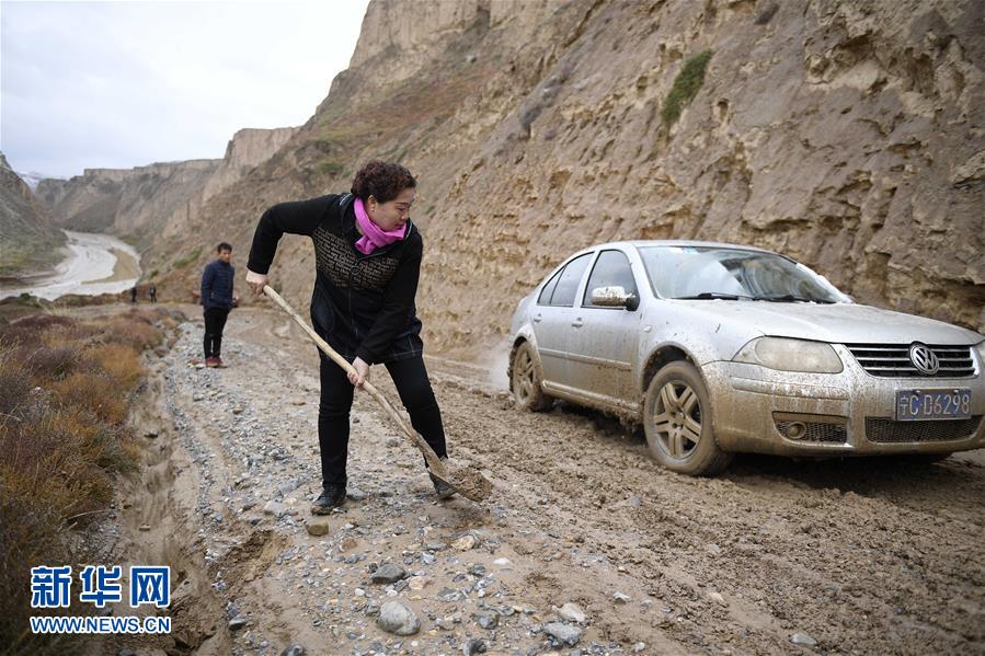 由于降雪,通往贺家塬村的路面泥泞湿滑,丁海燕帮助司机铲平道路(10月