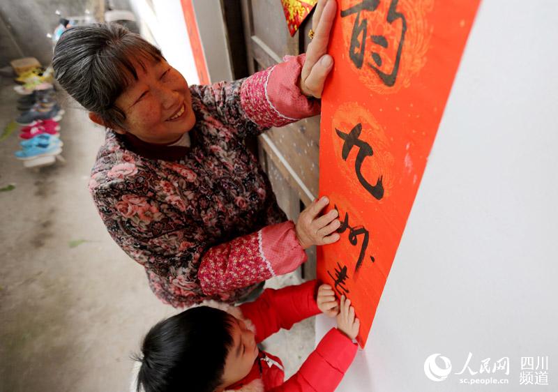 广安市前锋区龙塘街道办事处黄锋村村民正在贴春联。（陈定军 摄）