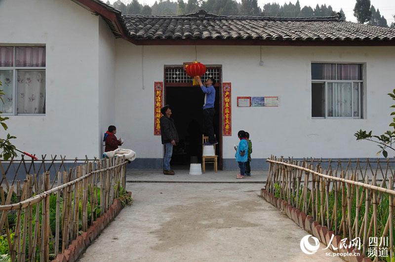 村民代杰在门前挂喜气的红灯笼。（张枥 摄）