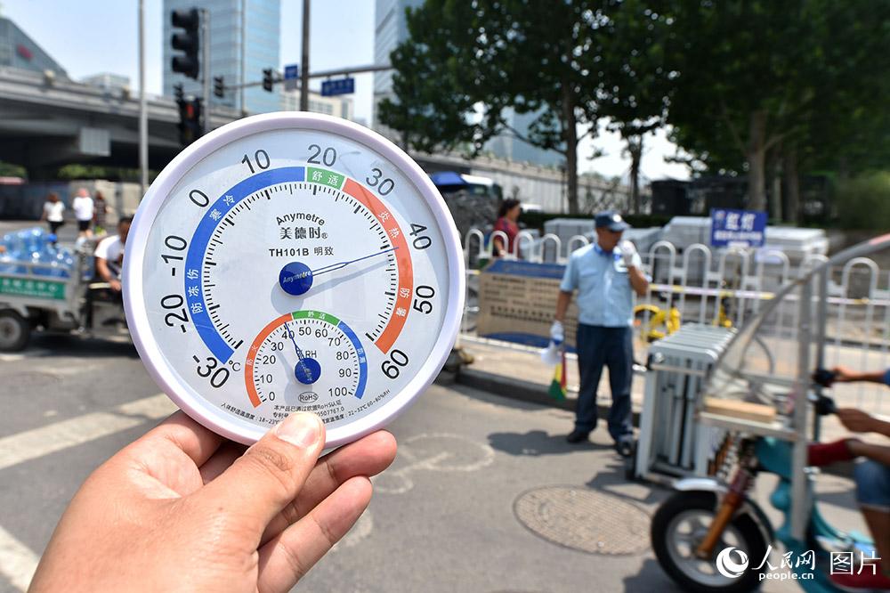 7月11日11点，北京CBD，交通协管员正在疏导交通。此时，烈日下的气温已超过40摄氏度，地表温度接近50摄氏度。（人民网记者 翁奇羽 摄）