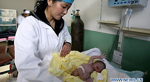 Yangzom wraps up the newborn in the delivery room in Maizhokunggar People's Hospital in Maizhokunggar County, southwest China's Tibet Autonomous Region, June 24, 2011.