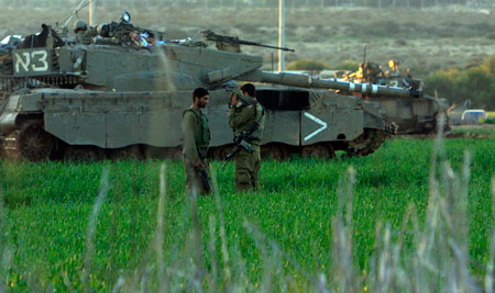 Two Israeli soldiers rest beside the tank in the Gaza Strip on January 6, 2009. The Israeli army has said that it would hold fire in the Gaza Strip for three hours every day from January 7 to allow local residents to prepare basic supplies.