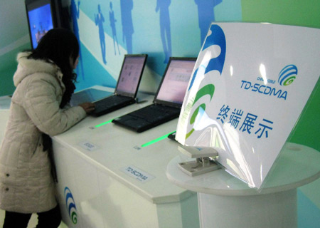 A girl tries the internet functions of a third-generation (3G) mobile phone at a China Mobile exhibition hall in Beijing, China, on January 7, 2009.