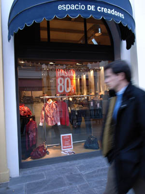 Pedestrians pass by a store window with discount signs in center of Madrid, capital of Spain on January 8, 2009. [Xinhua]
