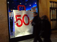 Pedestrians look through a store window with discount signs in center of Madrid, capital of Spain on January 8, 2009. The winter sales in Madrid kicked off on January 7 offering more discounts this year because of the global financial crisis.