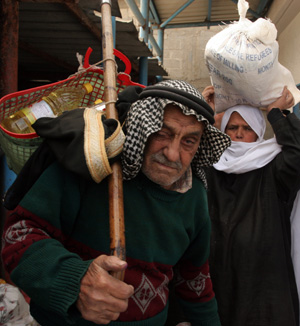 Palestinian refugees receive food in aid from an office of the United Nations in Gaza City on January 8, 2009. The United Nations halted aid deliveries to the besieged Gaza Strip on Thursday, citing Israeli attacks on its staff and installations hours after it said gunfire from an Israeli tank killed one of its drivers as he was picking up a shipment. [Xinhua]