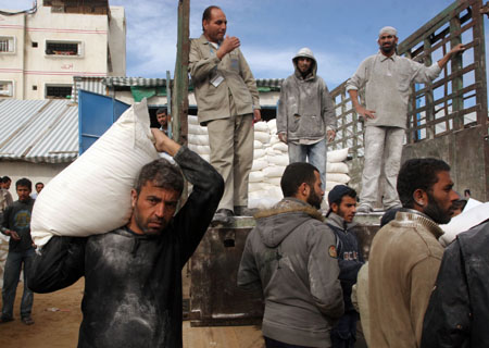 Palestinian refugees receive food in aid from an office of the United Nations in Gaza City on January 8, 2009. The United Nations halted aid deliveries to the besieged Gaza Strip on Thursday, citing Israeli attacks on its staff and installations hours after it said gunfire from an Israeli tank killed one of its drivers as he was picking up a shipment. [Xinhua]