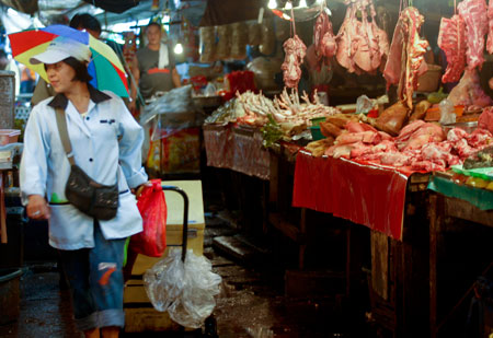 A milk vendor passes by the meat section of a market in Manila, capital of the Philippines, on January 8, 2009. A team of international experts is investigating the Ebola Reston virus found in pigs at two farms in the northern Philippines, the World Health Organization (WHO) said on Thursday.