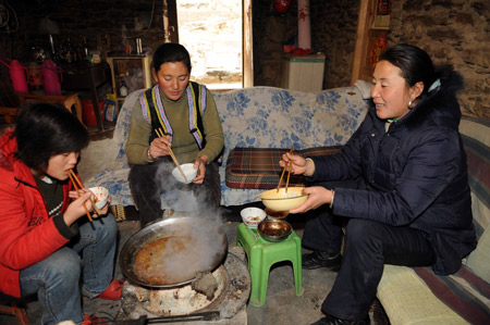 Chen Xiaohua (C) and her family members have lunch around a furnace at Lianhe Village, Longxi Town of Wenchuan County in southwest China's Sichuan Province, on January 8, 2009. Since the early November of 2008, local government of Sichuan Province had carried out various measures to keep the quake victims warm in the cold winter. 