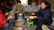 Chen Xiaohua (C) and her family members have lunch around a furnace at Lianhe Village, Longxi Town of Wenchuan County in southwest China's Sichuan Province, on January 8, 2009. Since the early November of 2008, local government of Sichuan Province had carried out various measures to keep the quake victims warm in the cold winter.