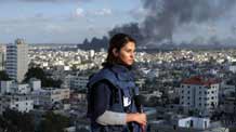 Shirn Tadros, Aljazeera International correspondent in Gaza, covers the latest developments in Gaza Strip from the roof of a building in Gaza while a smoke rises behind him, on January 9, 2009. [Xinhua]