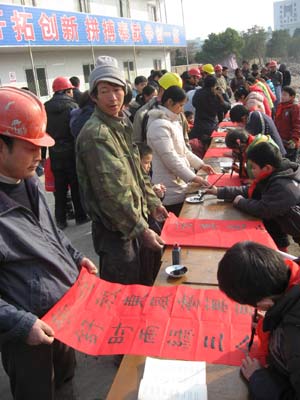 Children from a calligraphy training class write spring couplets for the laborers on a construction site in Chaohu City, east China's Anhui Province, on January 11, 2009, to welcome the forthcoming Chinese traditional Spring Festival which falls on January 26 this year. 