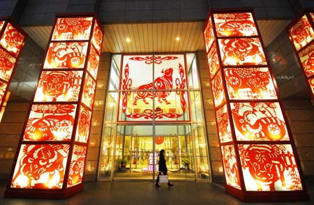 A pedestrian passes the door of a shopping mall decorated with the paper-cut work with the theme of the Year of Ox on the Nanjing Road in Shanghai, China, on January 13, 2009. As the Year of Ox in Chinese lunar calendar approaching, the city is permeated with a holiday atmosphere. The Chinese Year of Ox will start from January 26, 2009. 