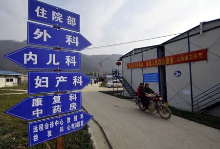 Residents drive near a hospital built under the help of east China's Shandong Province, in Leigu Town of Beichuan County, pounded by the May 12 devastating earthquake last year, southwest China's Sichuan Province, on January 12, 2009. People in Beichuan had engaged in reconstructing their hometown with 47,814 farmers' houses completed or being built, which account for 76 percent of the total.