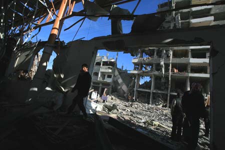 Palestinians walk past a building destroyed by Israeli strikes in Gaza City on January 13, 2009. Israeli soldiers fought heavy battles with local militants in Gaza early on Tuesday. Medics said Monday that over 900 people have been killed and more than 4,100 others wounded since Israeli military operation on December 27, 2008.